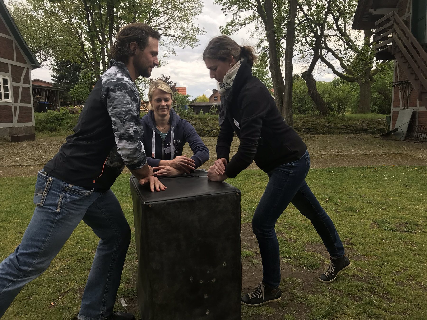 Students practising practitioner body mechanics on a training block outdoors.